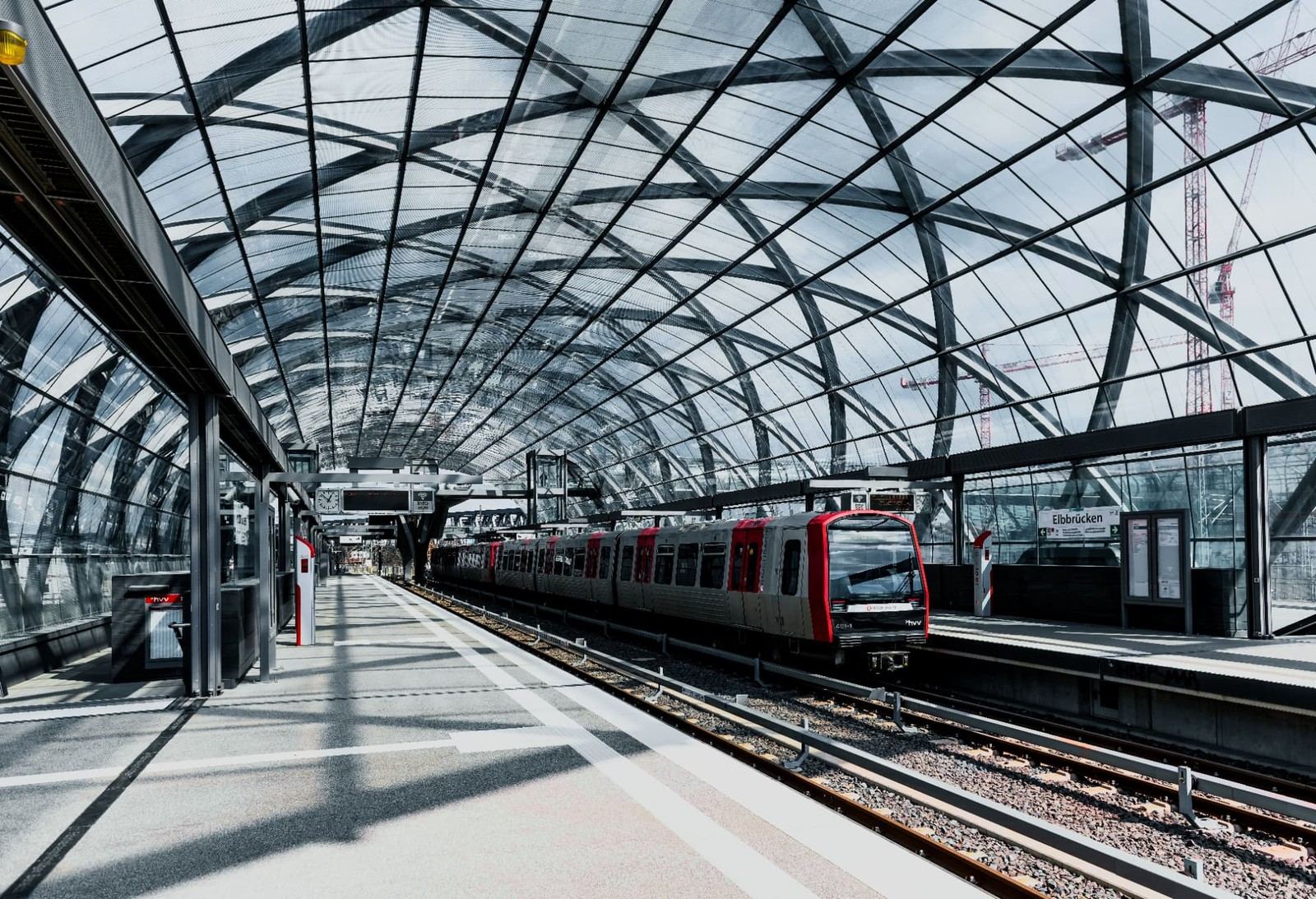 Modern glazed railway station canopy with a train arriving at the platform