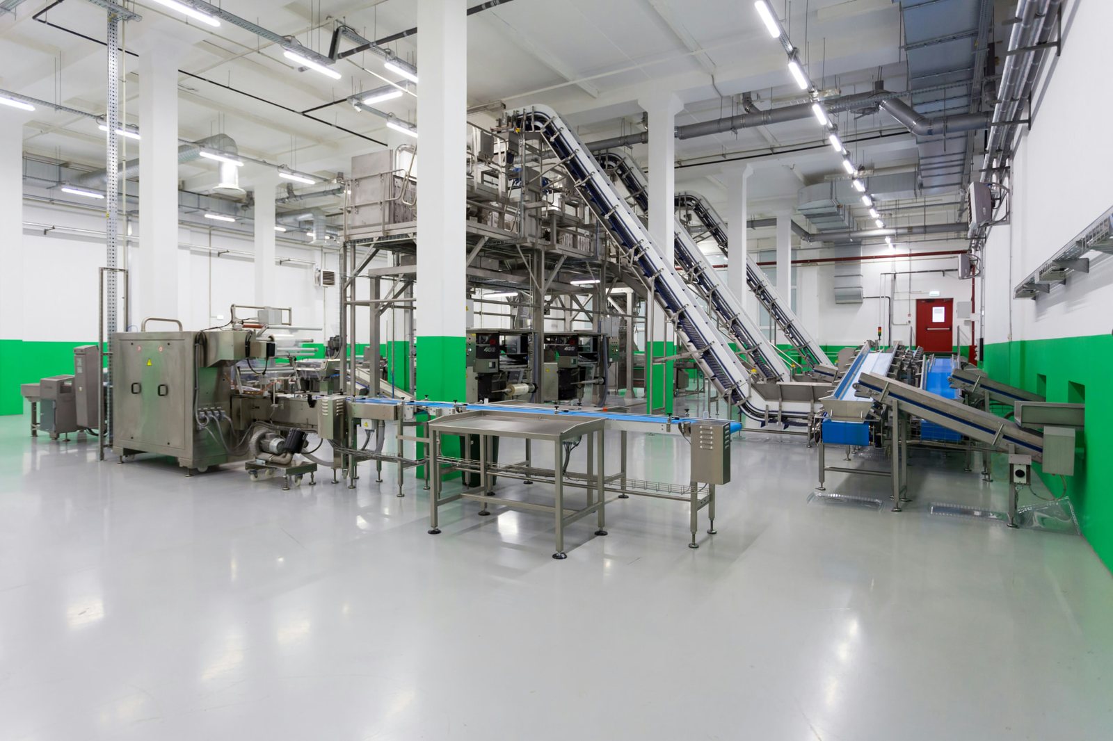 Stainless-steel processing line with inclined conveyors inside a modern process plant