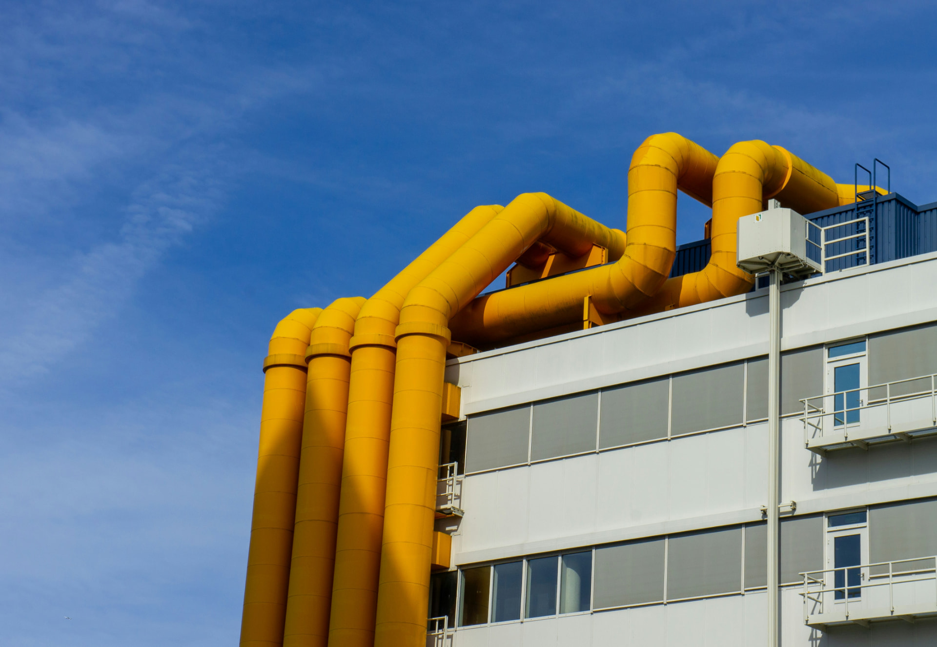 External industrial HVAC pipework and services mounted on the facade of a process building