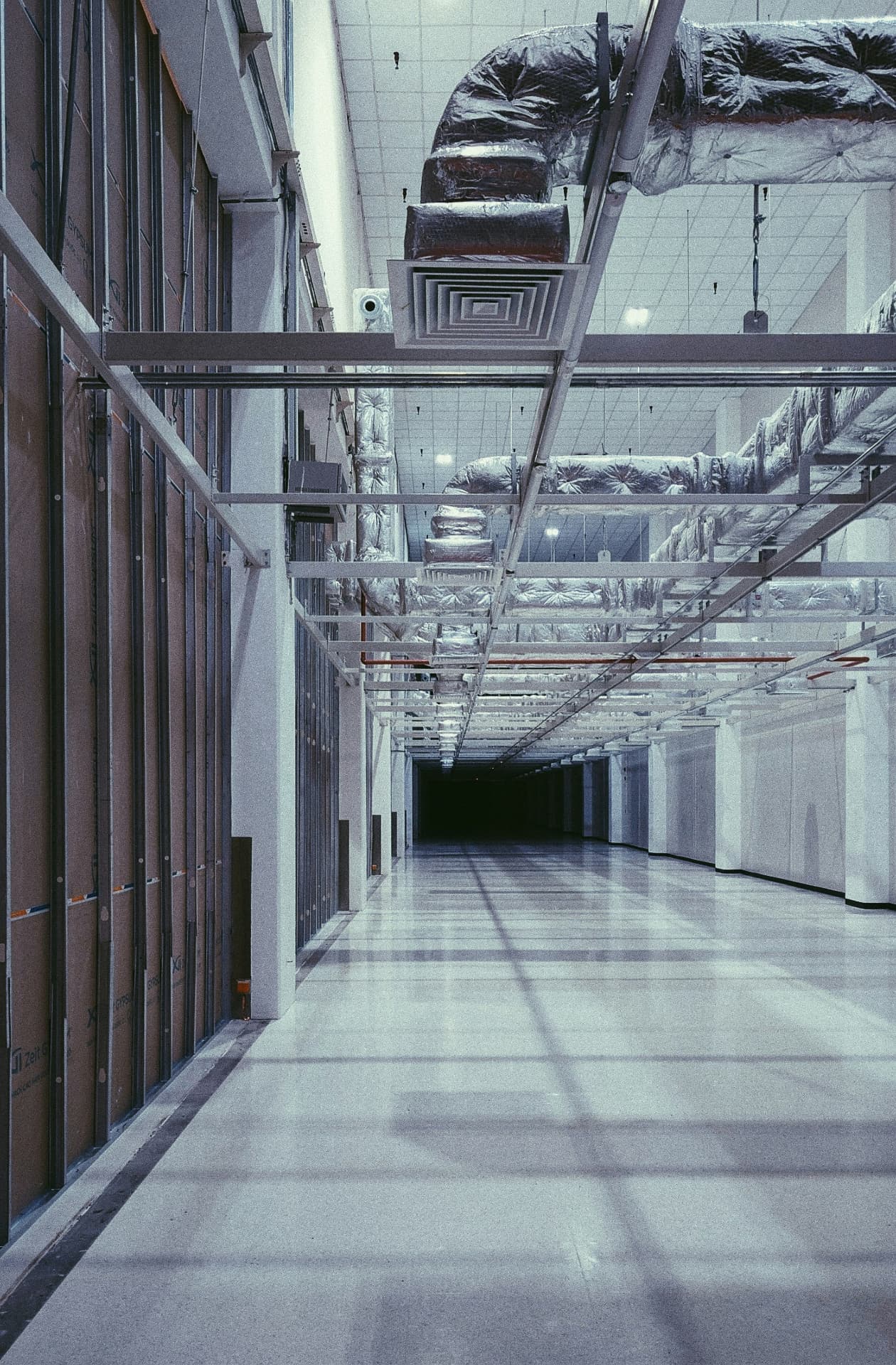 Overhead ventilation ductwork and building services running through an industrial hall